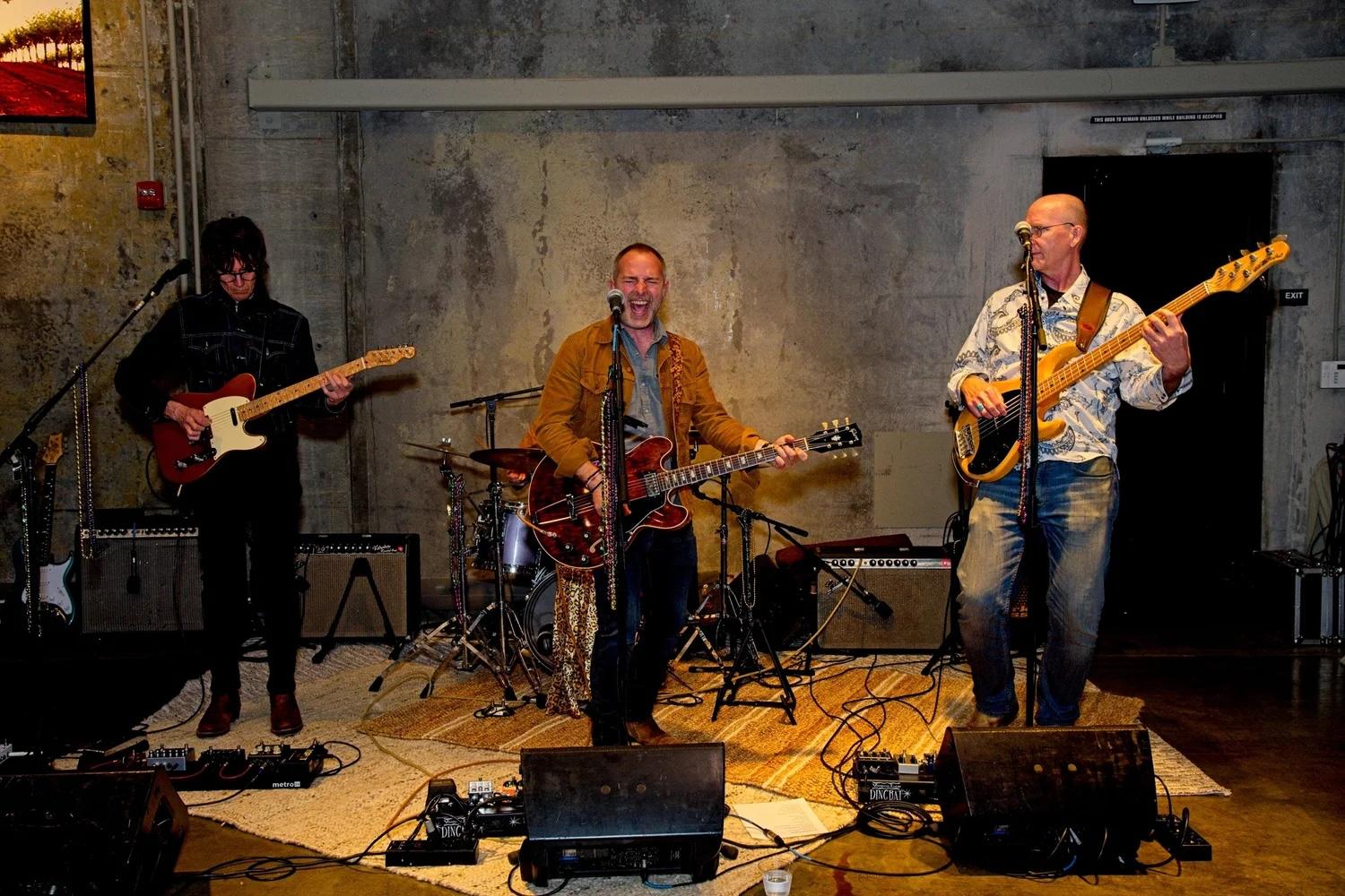 Three guitarists play and sing in a wine cellar at Louis Martini winery.